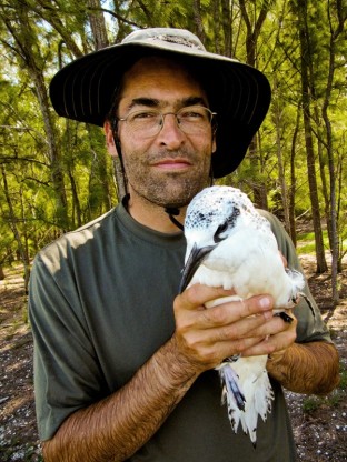 Chris Jordan at Midway Atoll holding a red-tailed tropicbird with a broken wing (courtesy of the Midway Project)